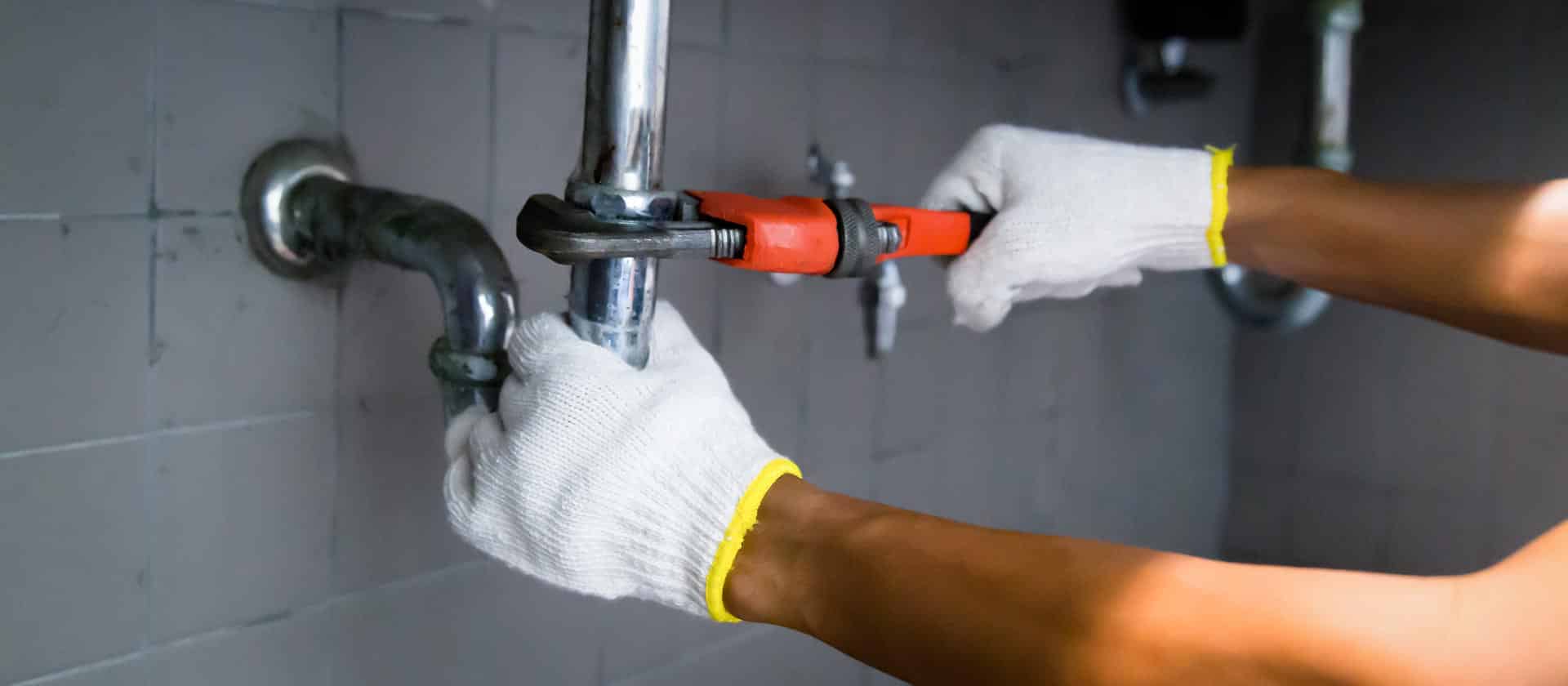 Plumber's Hand Repairing Sink Pipe Leakage With Adjustable Wrench.